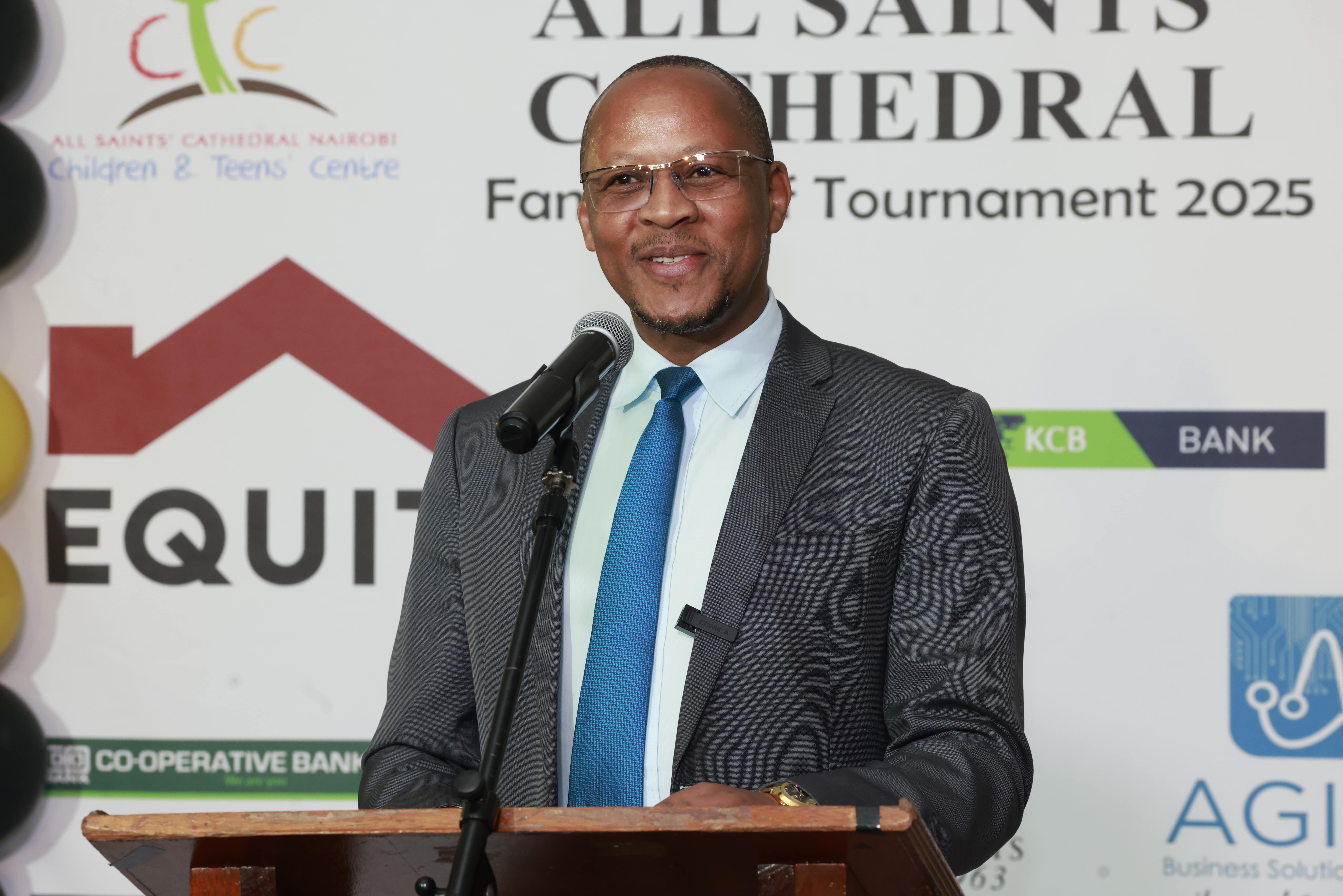 Man in a suit speaking at an All Saints' Cathedral event podium